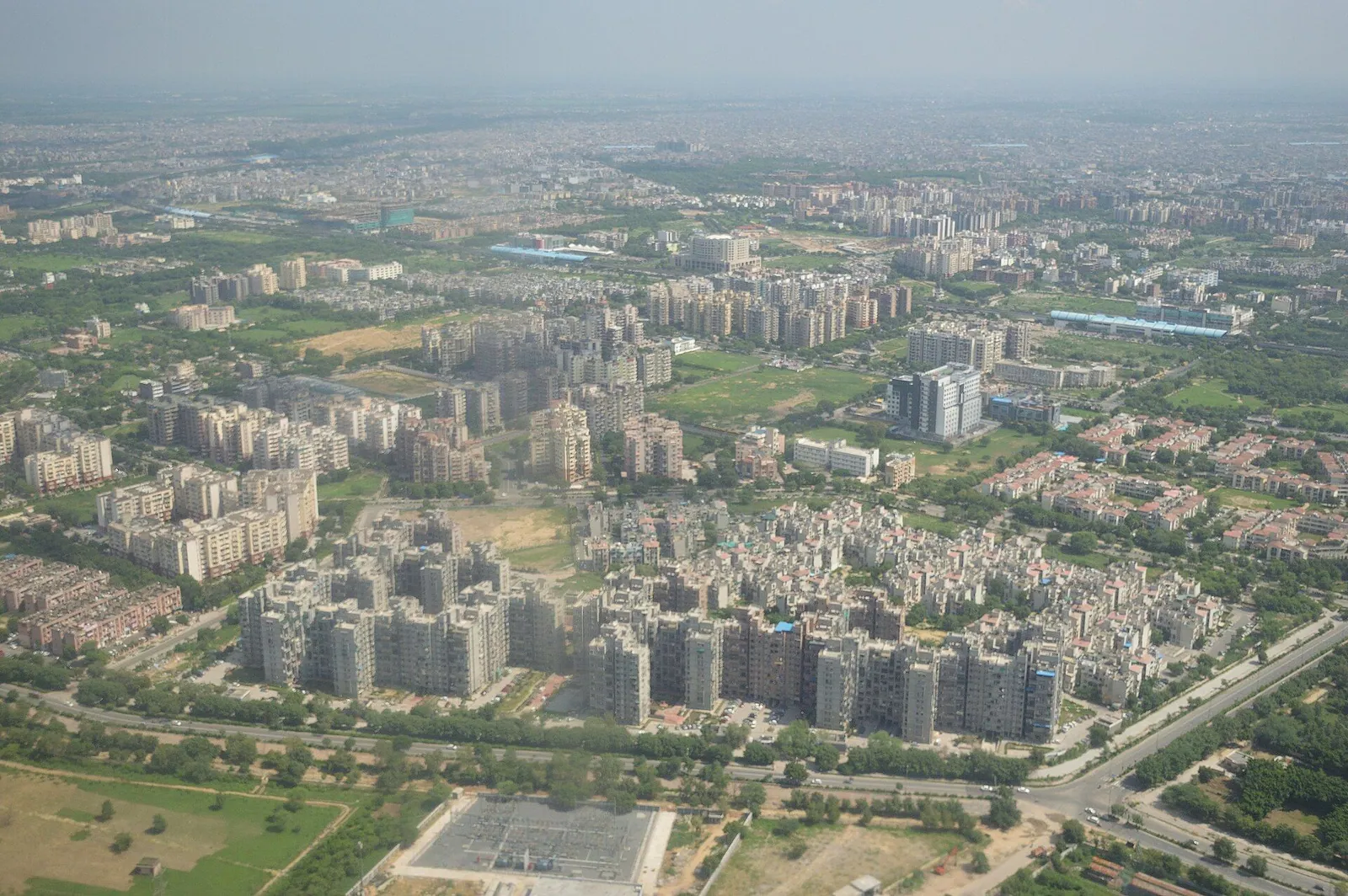 An aerial view of apartment blocks, roads and green spaces in Dwarka