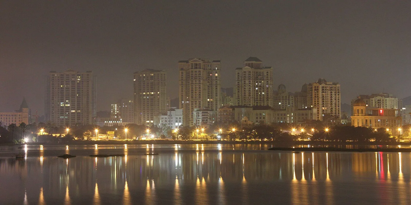 Residential towers lit at night, reflected in Powai Lake